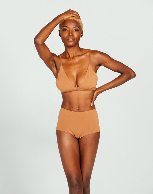Woman wearing a camel organic cotton boyshort underwear set on a light gray background