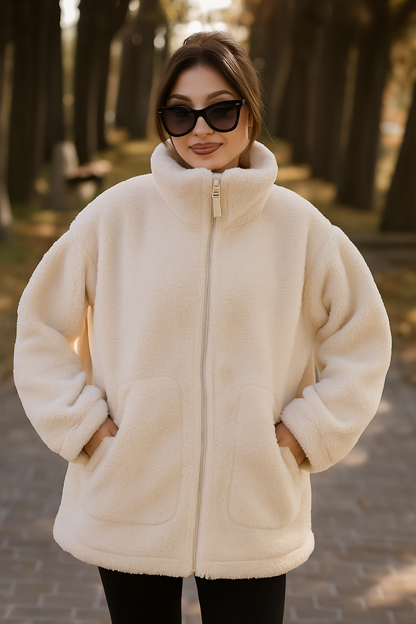 Woman wearing a cream-colored fleece jacket outdoors in a park setting.