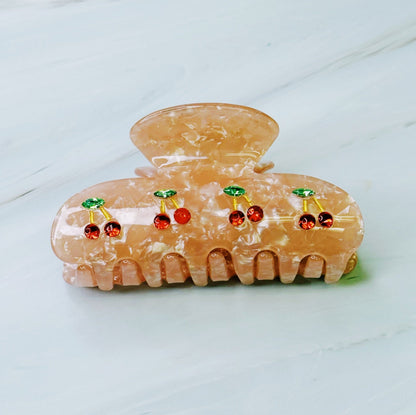 Decorative hair clip with cherry designs on a light background