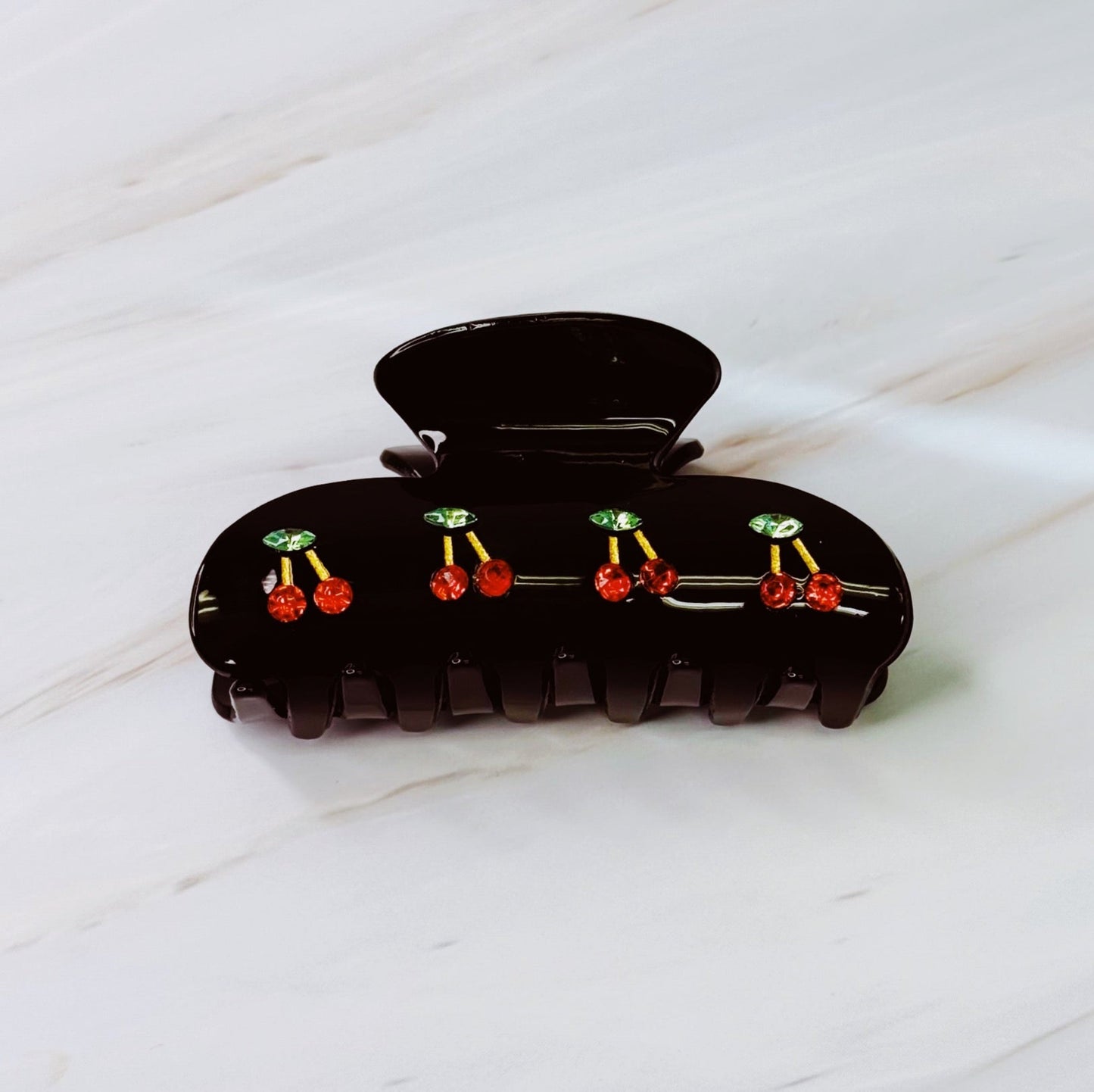 Black hair clip with red and green decorative elements on a white surface
