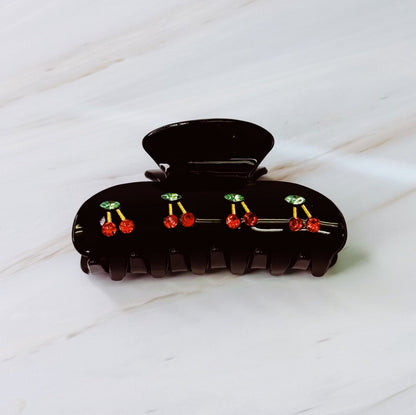 Black hair clip with red and green decorative elements on a white surface