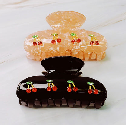 Two hair clips with cherry designs on a white surface
