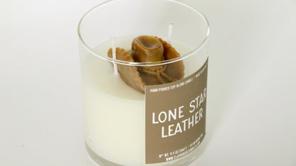 Candle in a glass jar with a label reading 'Lone Star Leather' on a white background