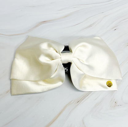 Large white bow  hair claw on a light wooden surface