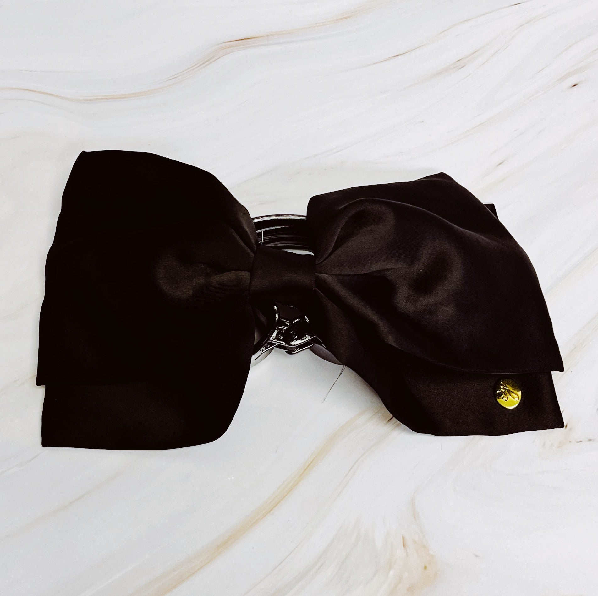 Black silk bow-shaped hair claw accessory on a light wooden surface