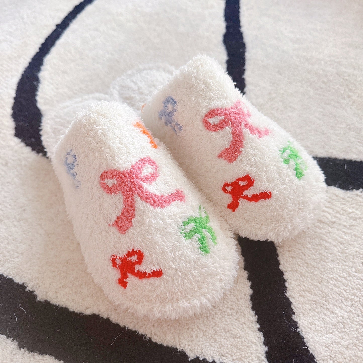 White fuzzy socks with colorful letters on a striped background
