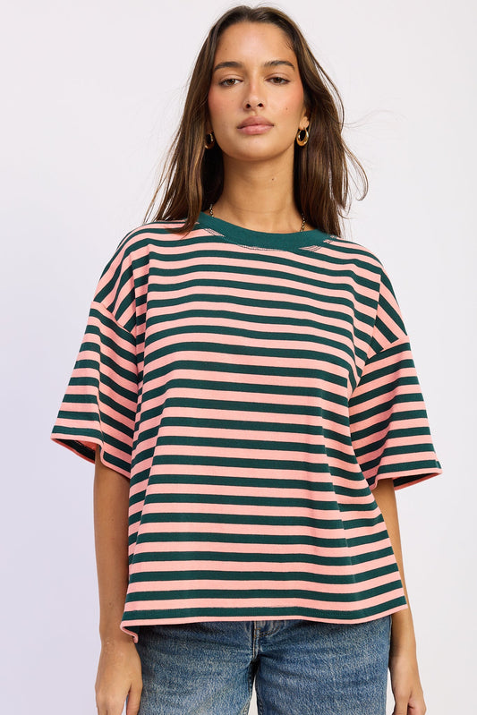Woman wearing a striped shirt with pink and green horizontal stripes on a plain background