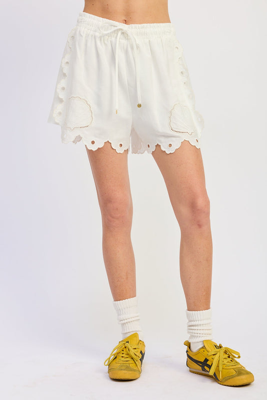 White lace shorts worn by a person on a white background