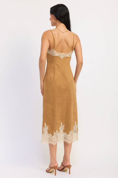 A woman shown from the back wearing a tan slip-style midi dress with cream lace trim at the neckline and hem, paired with tan heeled sandals against a plain light background.
