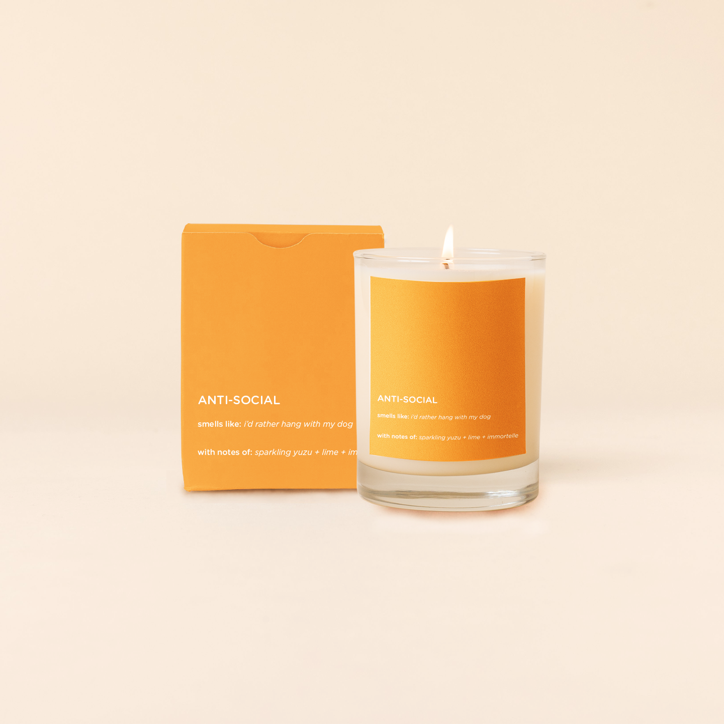 Anti-social Candle with orange label and packaging on a beige background