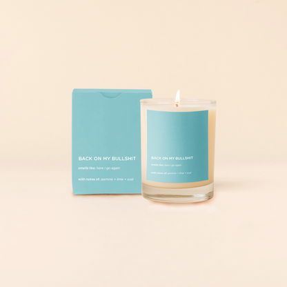 Candle with blue label and packaging on a beige background