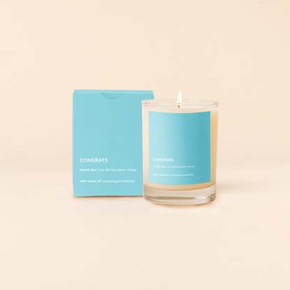 Congrats Candle with blue label and matching card on beige background