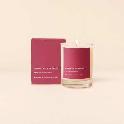 Legacy Candle with a red label and packaging on a beige background