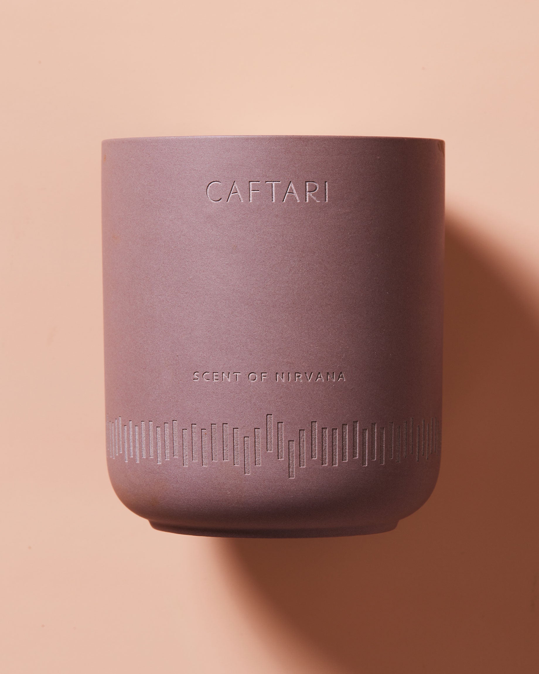 Purple candle with 'CAFTARI' branding on a peach background