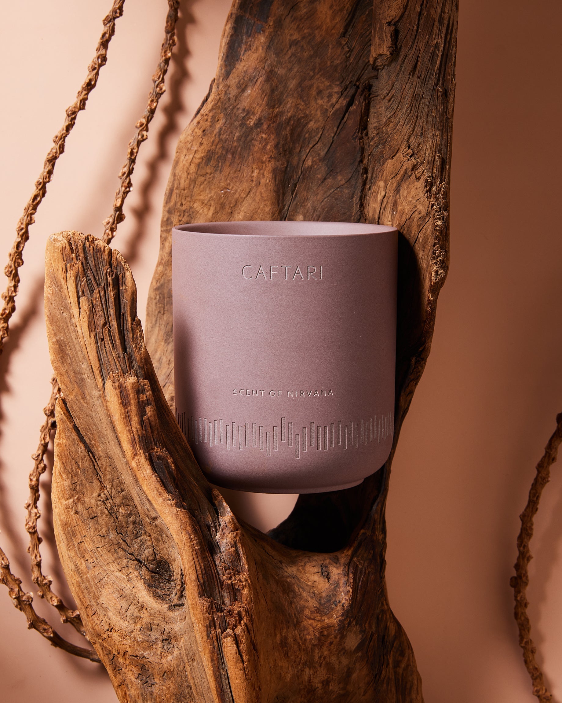 Purple candle with 'Caftari' branding on a wooden surface
