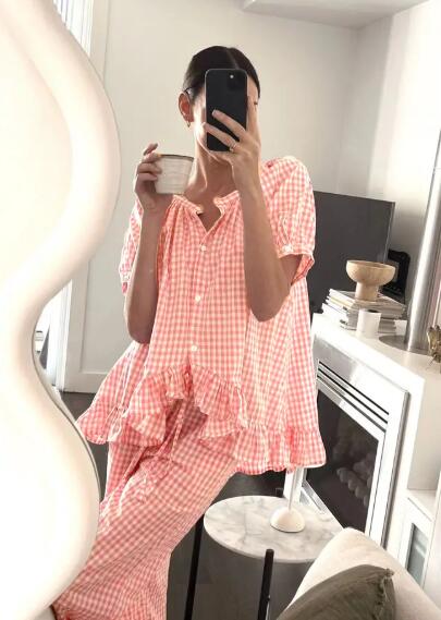 Person wearing a pink checkered outfit taking a mirror selfie.