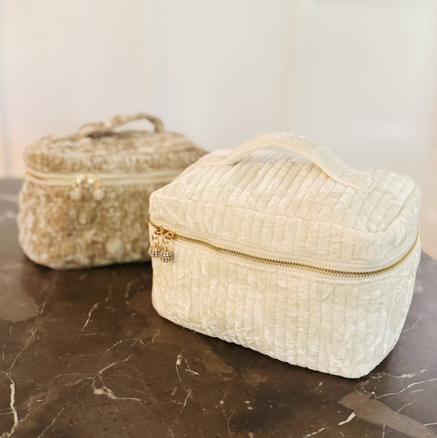 Two woven boxes with gold zippers on a marble surface