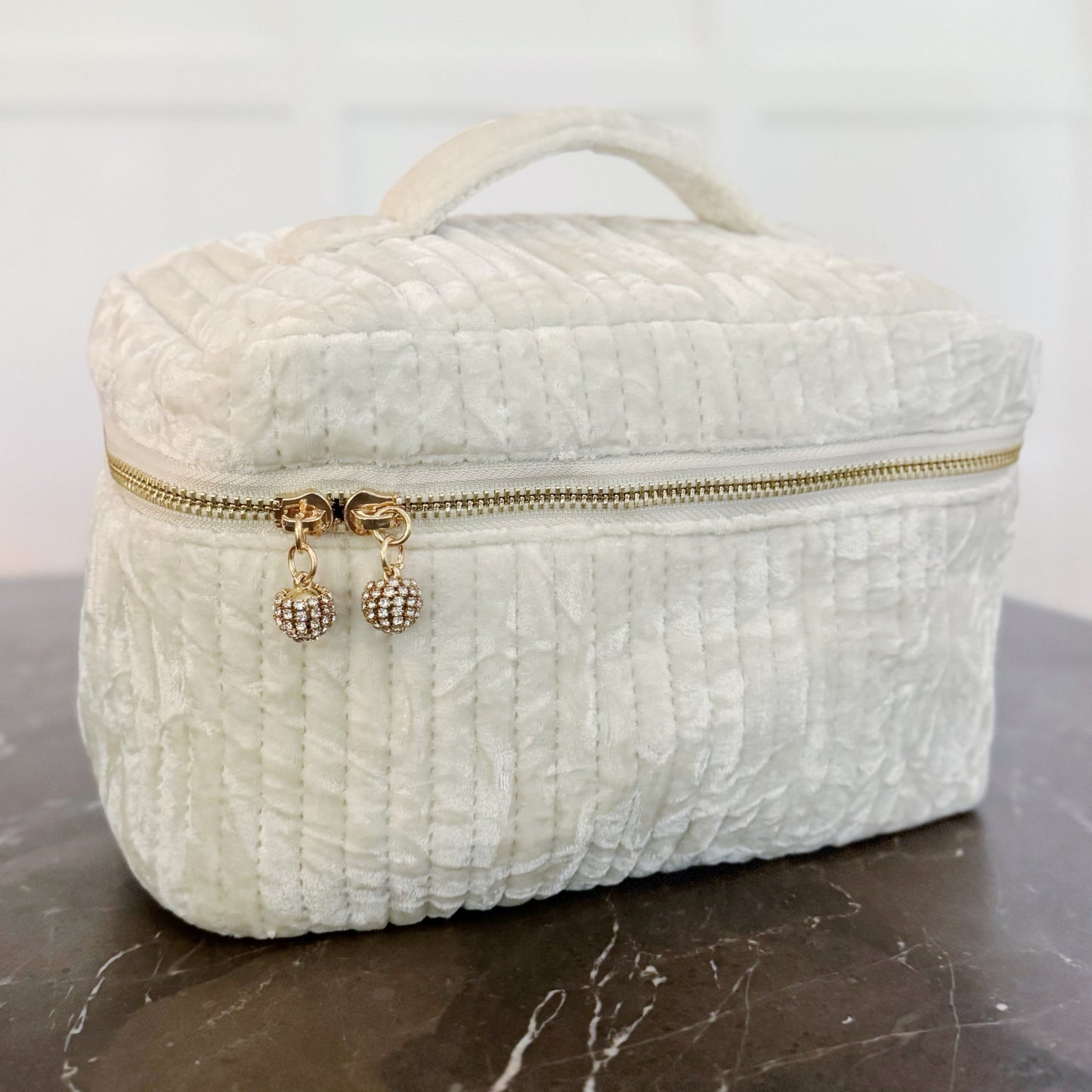 White textured makeup bag with gold zipper on a marble surface