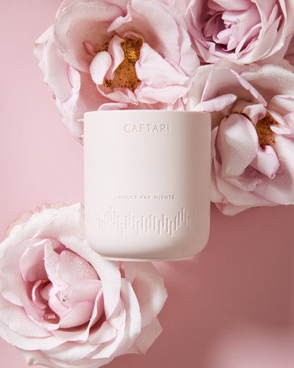 Caffarel candle surrounded by pink flowers on a pink background