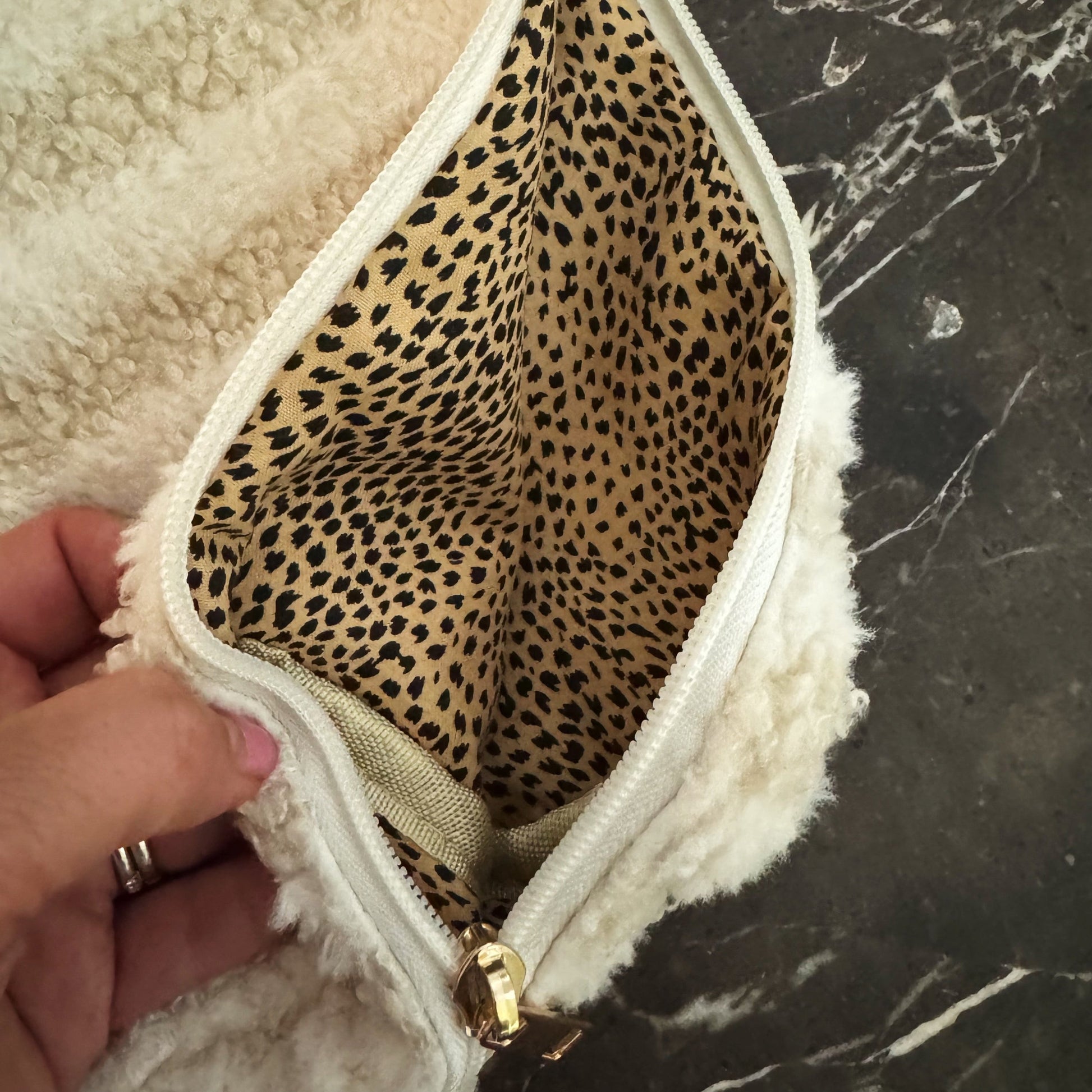 Close-up of a pouch with leopard print interior on a marble surface