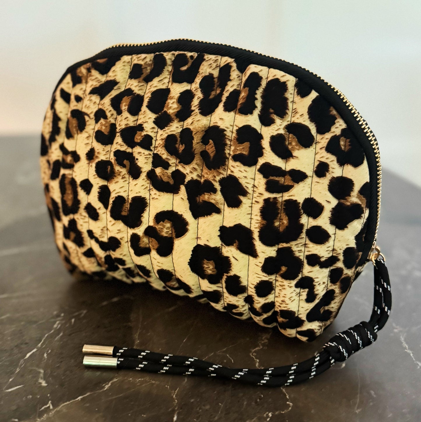 Leopard print clutch bag with a strap on a marble surface