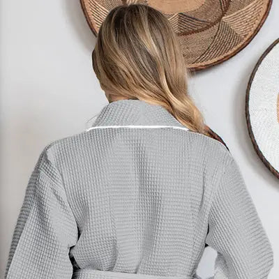 Person wearing a gray Waffle Kimono Knee-Length robe  with wicker baskets in the background