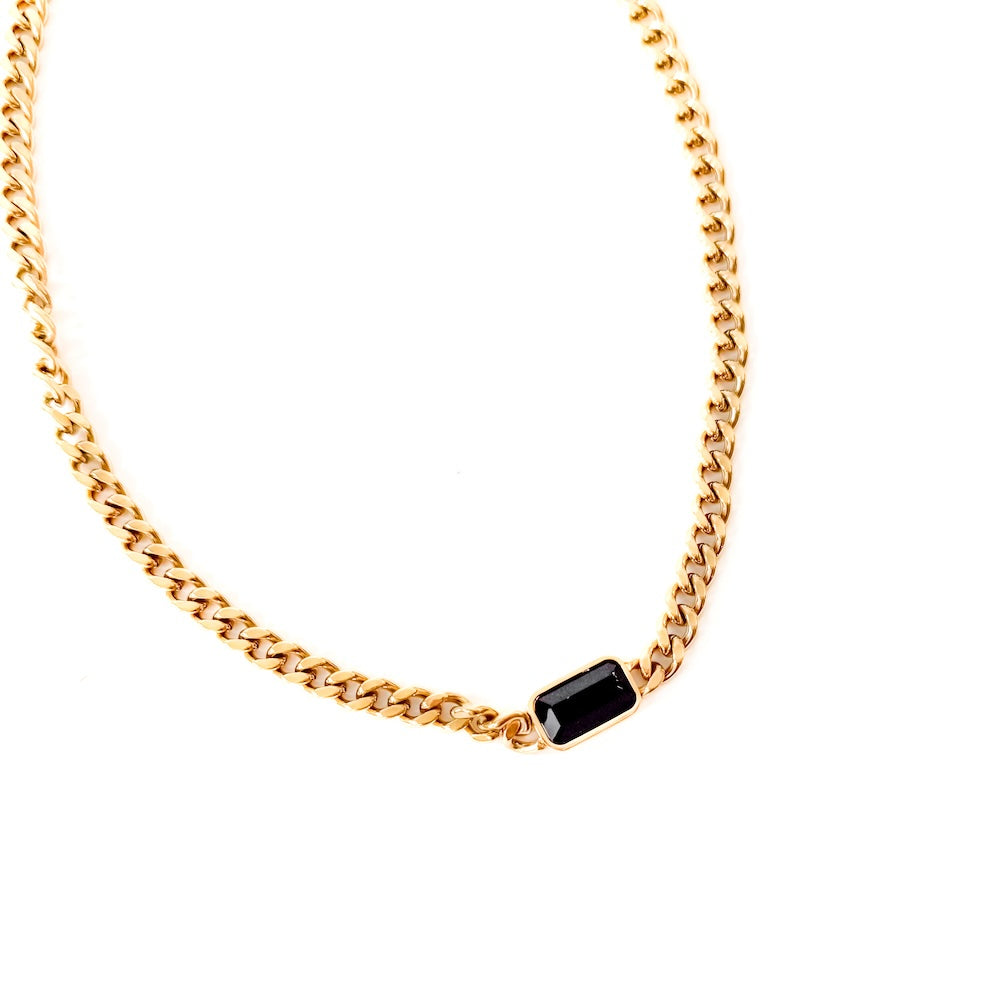 Gold chain necklace with a black gemstone on a white background