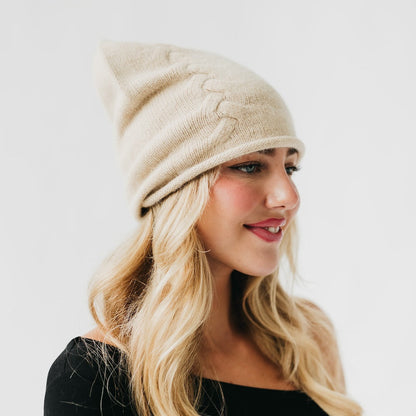 Woman wearing a beige knitted beanie on a white background
