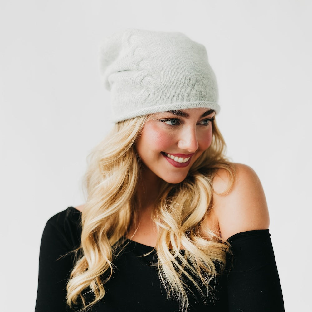 Woman wearing a gray knit beanie against a white background