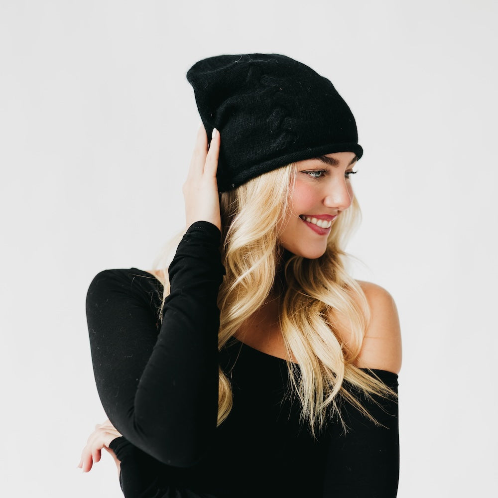 Woman wearing a black beanie and black outfit against a white background