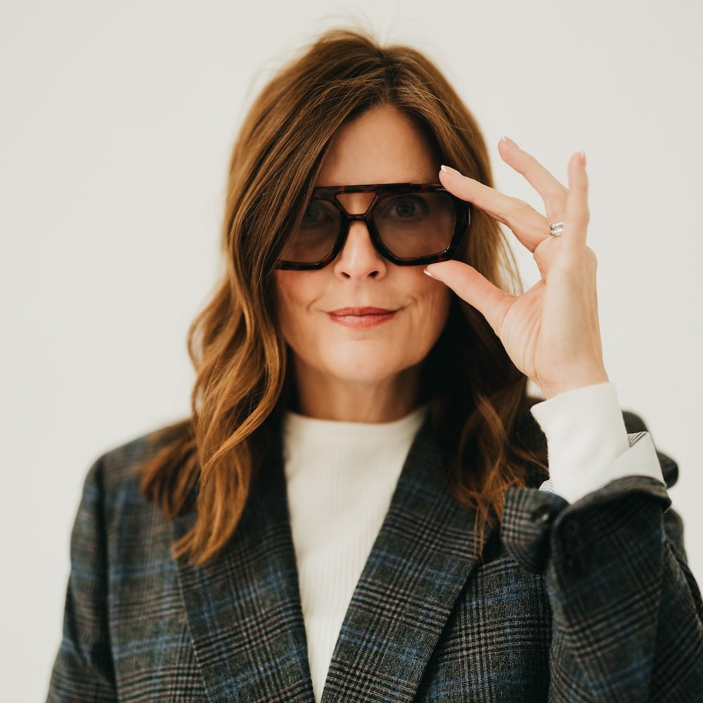 Woman adjusting 3D glasses with a plain background