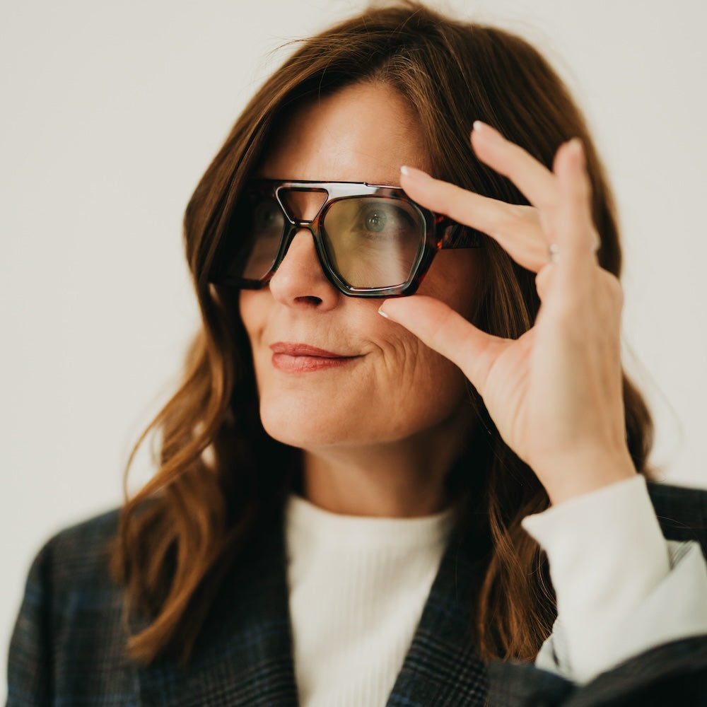 Woman wearing sunglasses and making a peace sign with her hand.