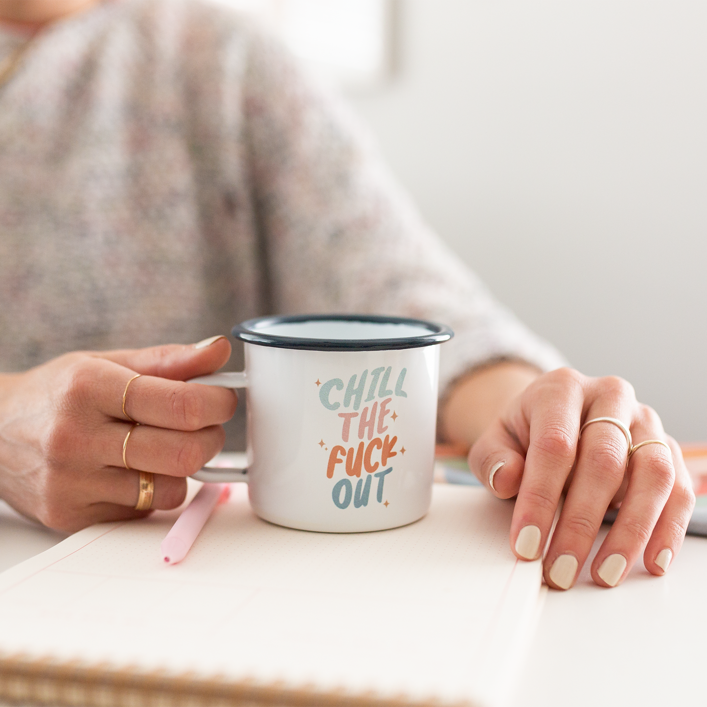 Person holding a mug with 'Chill The F*** Out' text on a light background