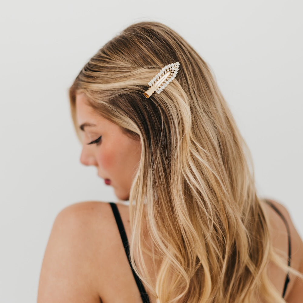 Woman with long blonde hair wearing a Pearl and Diamond hair clip on a plain background