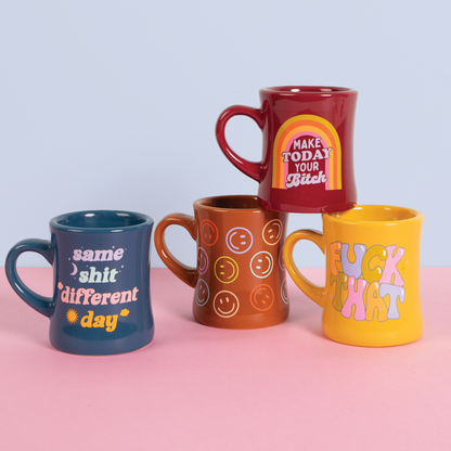 Four colorful mugs with various designs on a pink and blue gradient background