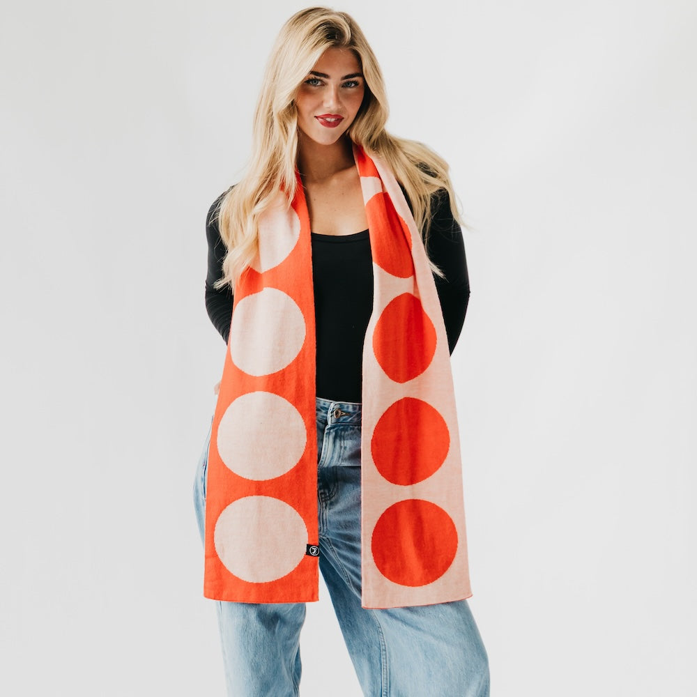 Woman wearing a large orange and beige polka dot scarf on a white background
