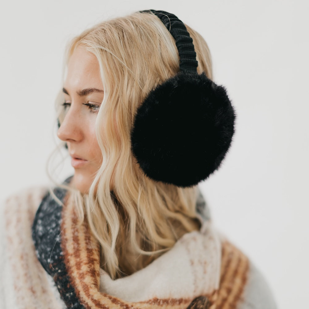 Person wearing black earmuffs with a plain background