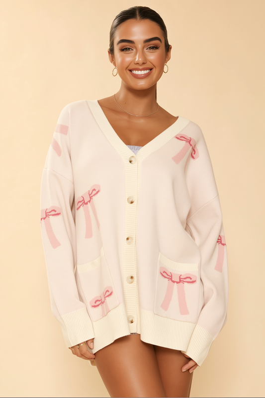 Woman wearing a cream cardigan with pink bows on a beige background