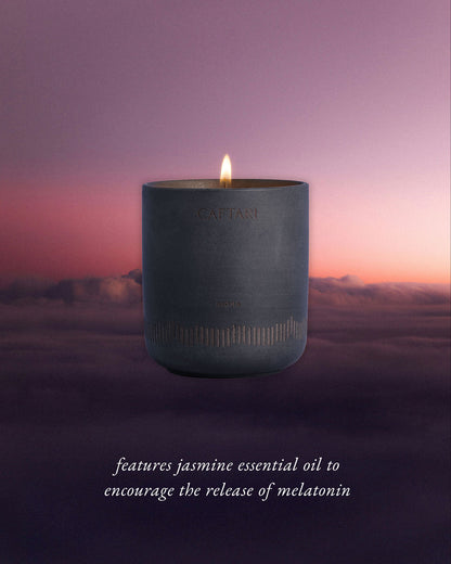 Candle in a gray container with a purple sky and clouds in the background