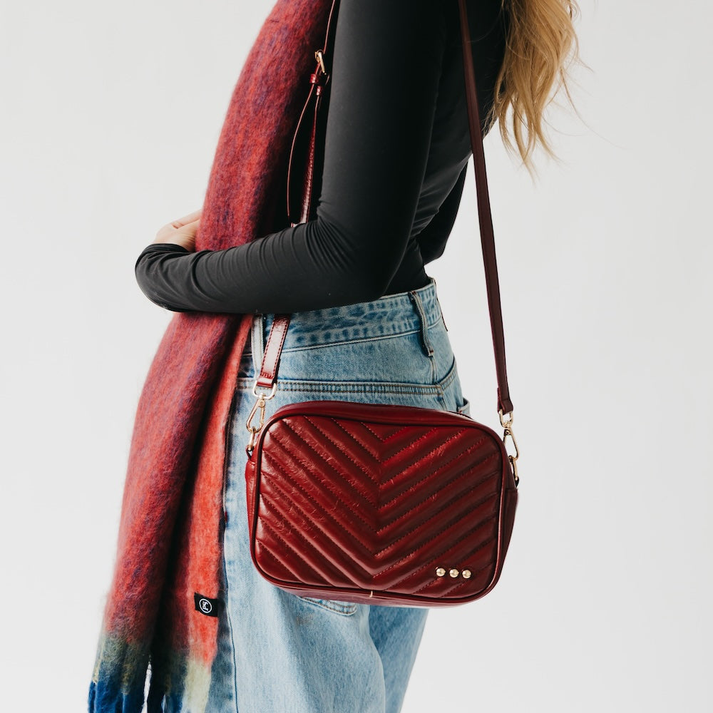 Person holding a red velvet handbag with a white background