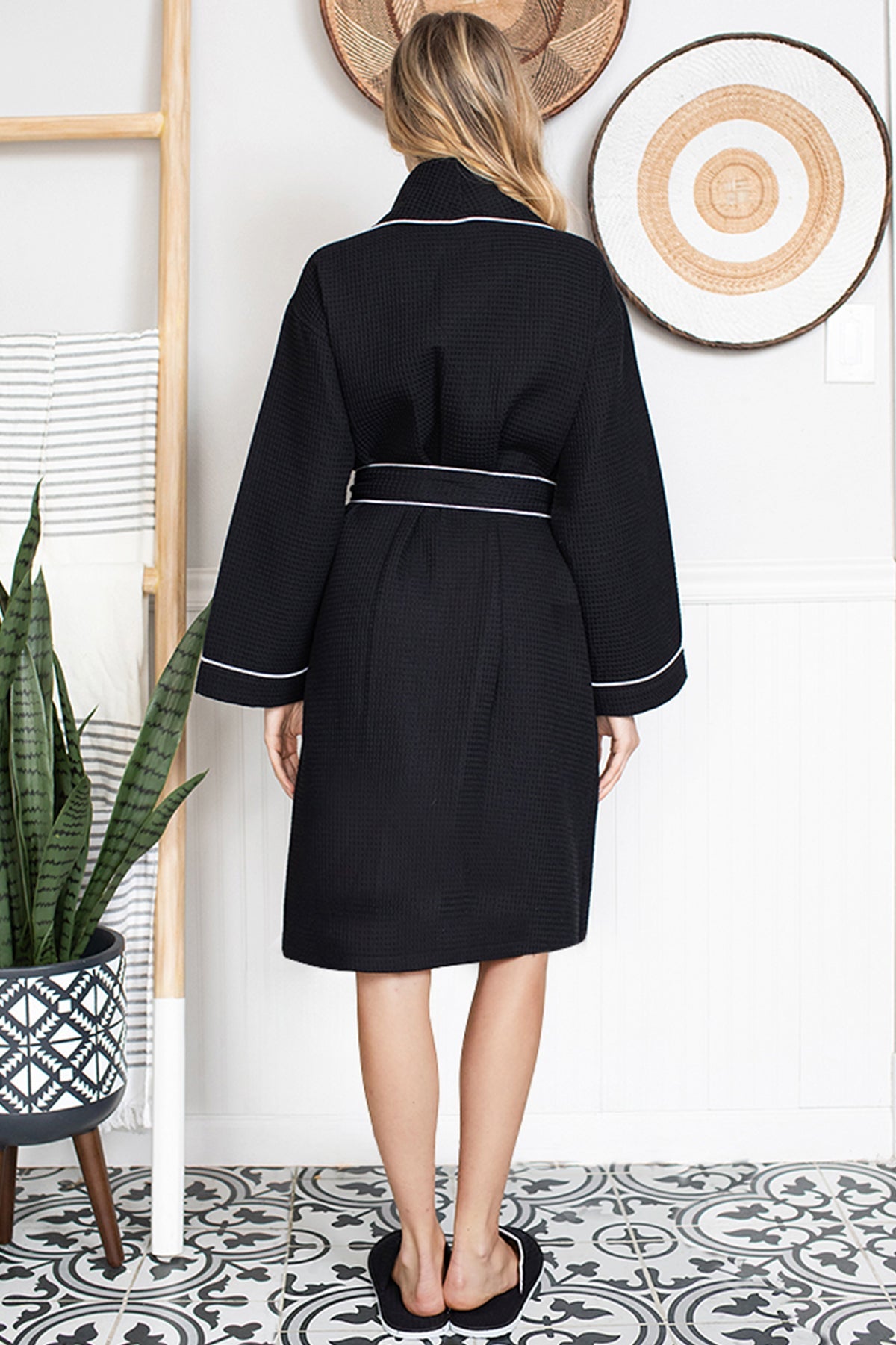 Person wearing a black Waffle Kimono Knee-Length robe with white trim in a room with decorative elements.
