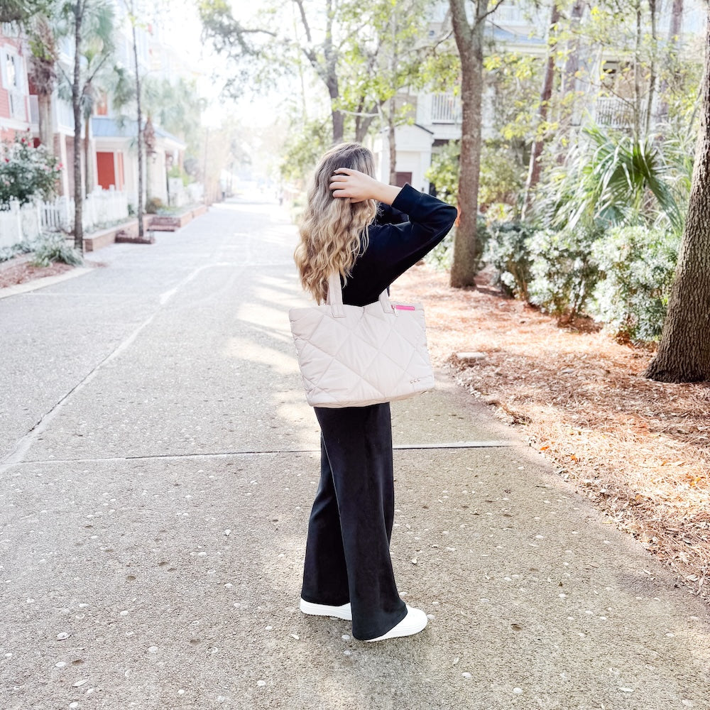 Woman walking down a street holding a white tote bag