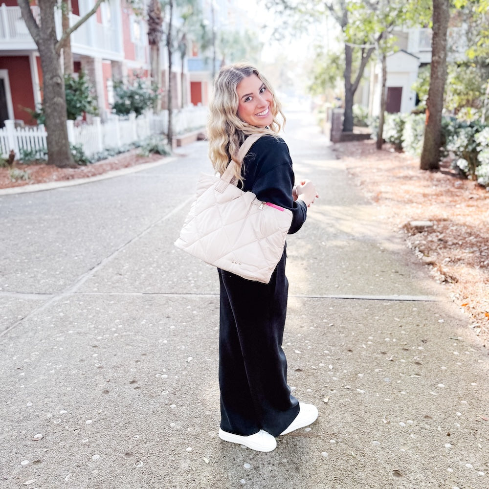 Woman holding a beige quilted handbag on a street
