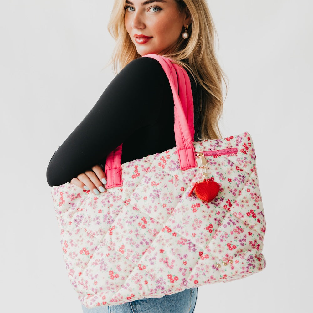 Woman holding a floral tote bag with a red heart on a plain background