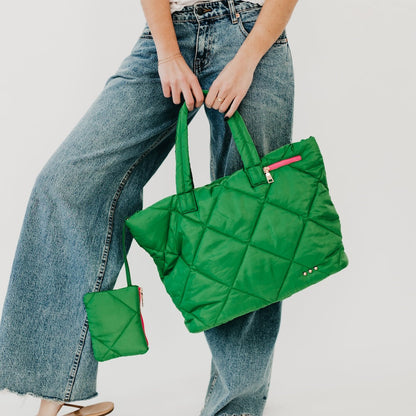 Person holding a green quilted handbag with a smaller matching pouch.