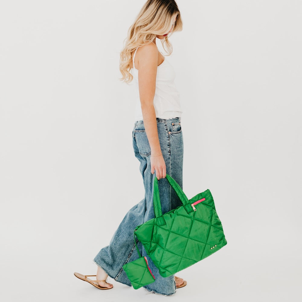 Woman holding a green quilted bag against a white background