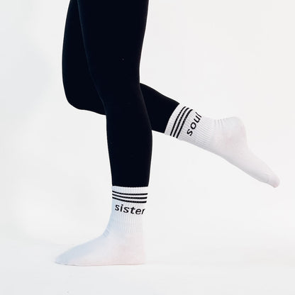 White socks with 'sister' and 'soul' text worn with black leggings on a white background