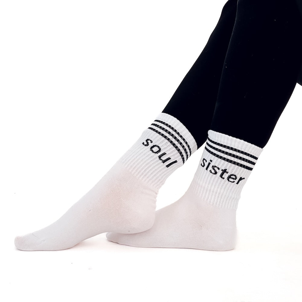 White socks with 'soul sister' text worn by a person on a white background