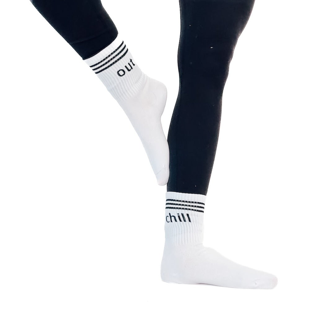 White socks with black text "chill" "out" and stripes worn by a person on a white background