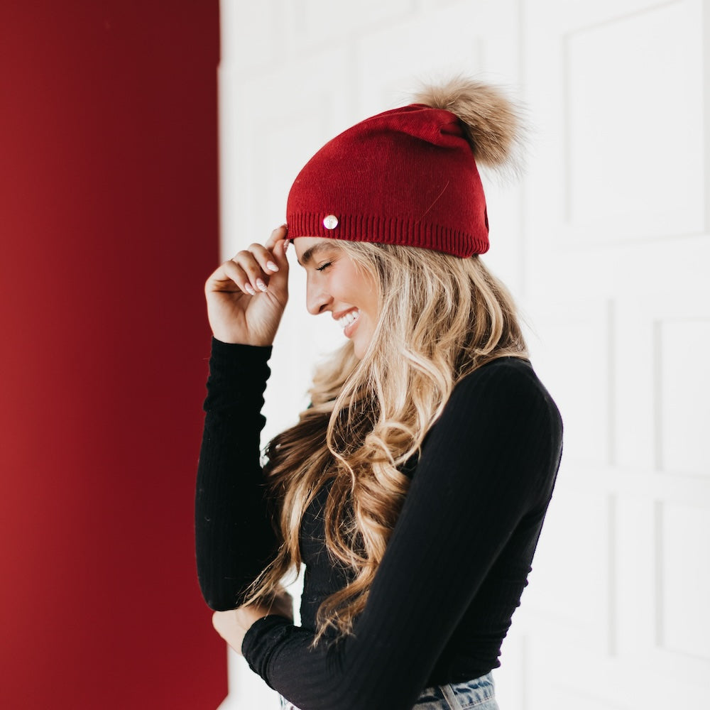 Woman wearing a red beanie with a pom-pom against a white and red background